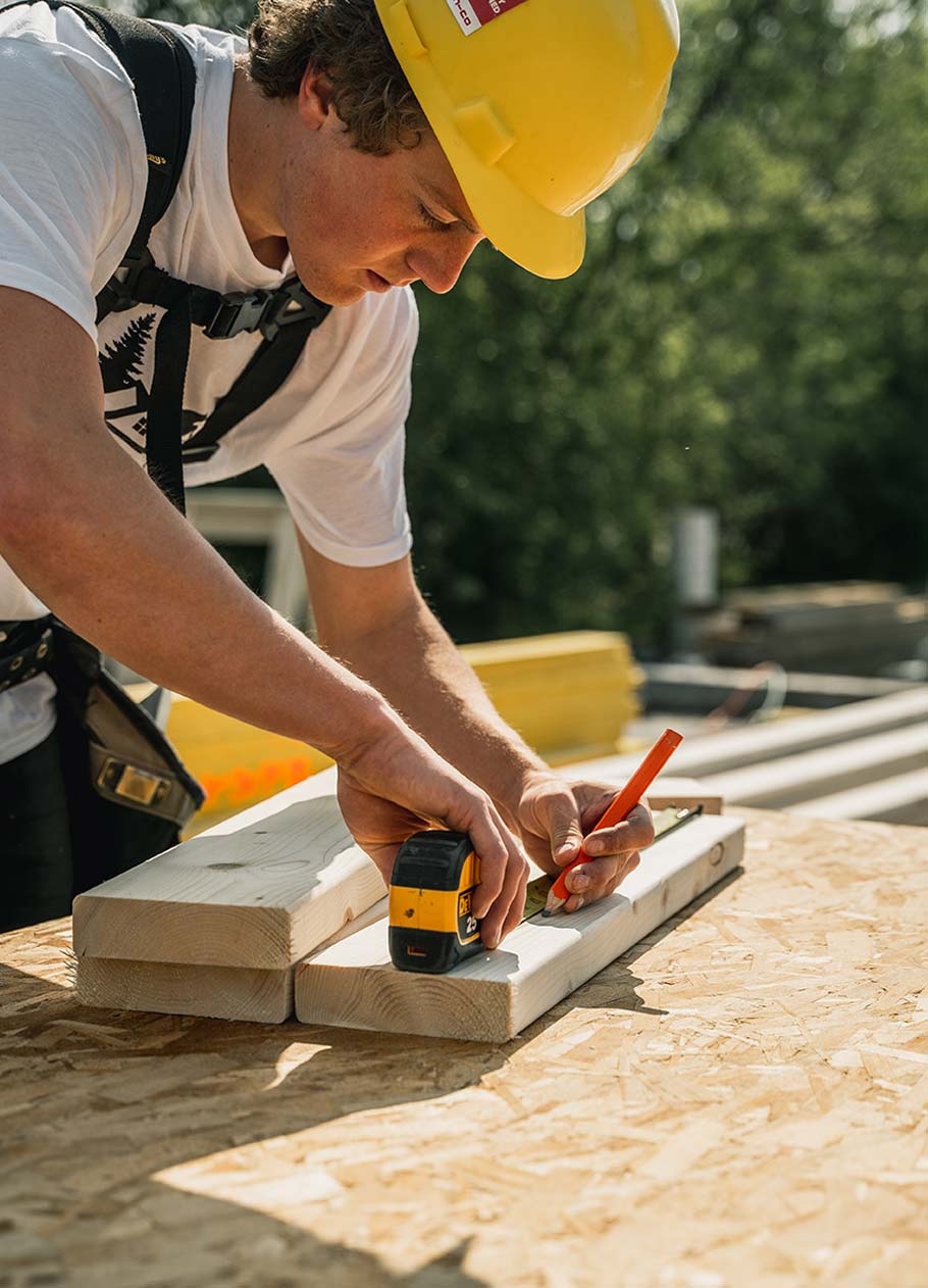 Carpenter measuring a 2x4 at the cut station.